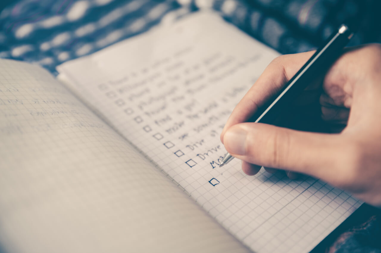 Hand writing with ink pen on grid paper in a notebook.
